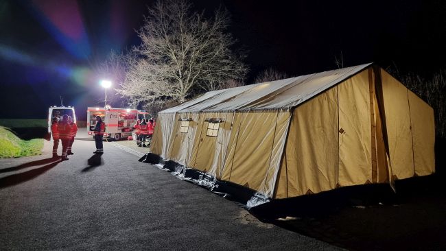 zu sehen ist ein aufgebautes Zelt und zwei Fahrzeuge des DRK
