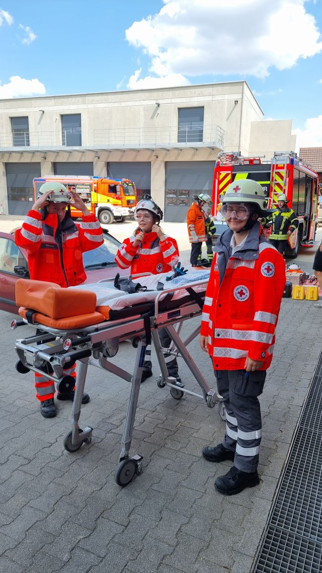 zu sehen sind DRK-Helfer mit einer Rettungstrage und im Hintergrund Feuerwehrfahrzeuge, bei einer gemeinsamen Übung