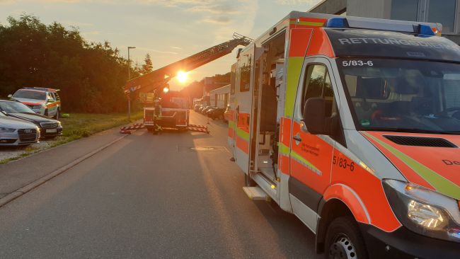 zu sehen ist ein Rettungswagen und im Hintergrund die Drehleiter der Feuerwehr bei einem Einsatz mit Sonnenuntergang