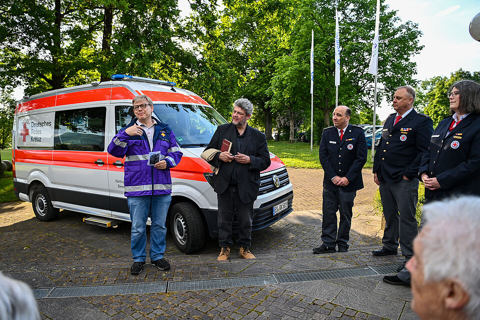 zu sehen ist das neue DRK-Fahrzeug, die beiden Weilheimer Pfarrer und die Bereitschaftsleitung des DRK