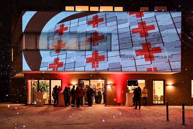 zu sehen ist eine Lichtpräsentation eines DRK-Logos auf die Eingangswand des Löwensaals Weilheim