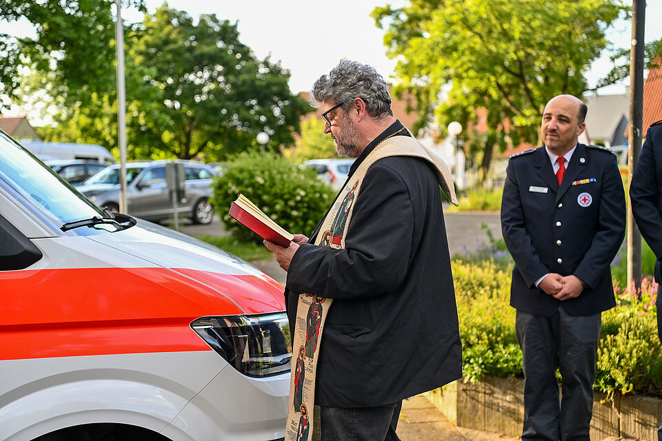 zu sehen ist Pfarrer Marx bei der Segnung des neuen DRK-Fahrzeugs
