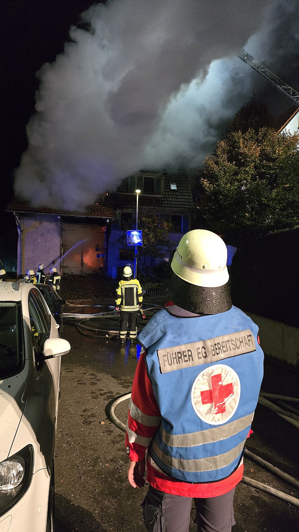 zu sehen ist das Brandgebäude im Hintergrund und im Vordergrund der Einsatzleiter der DRK-Bereitschaft