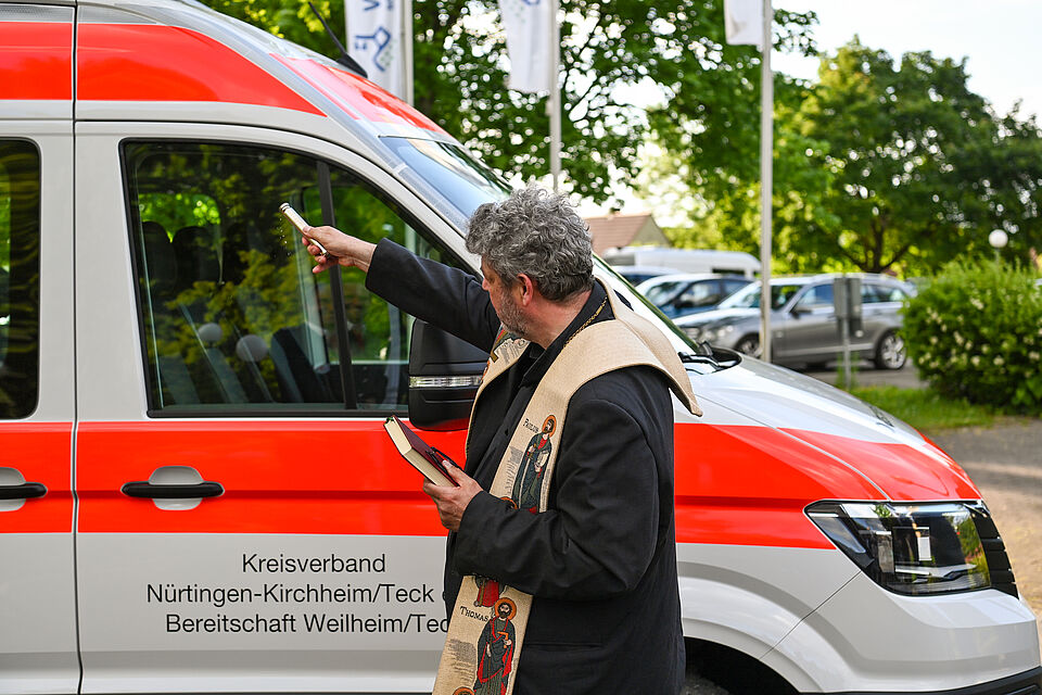 zu sehen ist Pfarrer Marx bei der Segnung des neuen DRK-Fahrzeugs