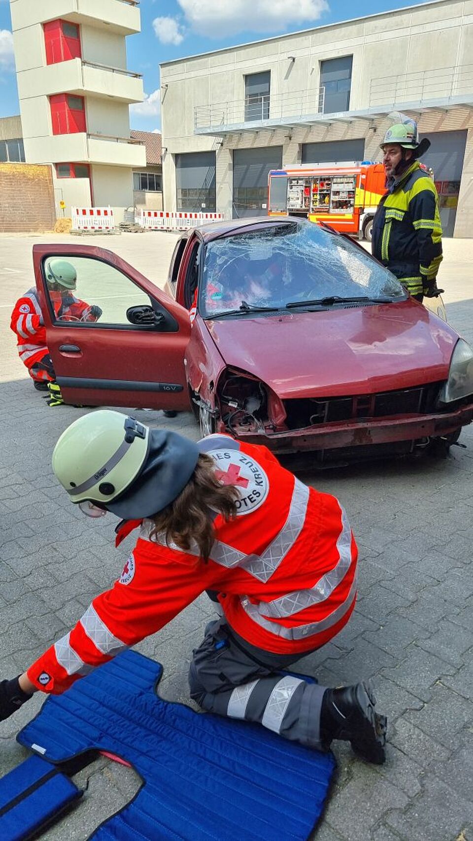 zu sehen ist das Übungsfahrzeug und im Vordergrund DRK-Helfer welche Rettungsmaßnahmen vorbereiten