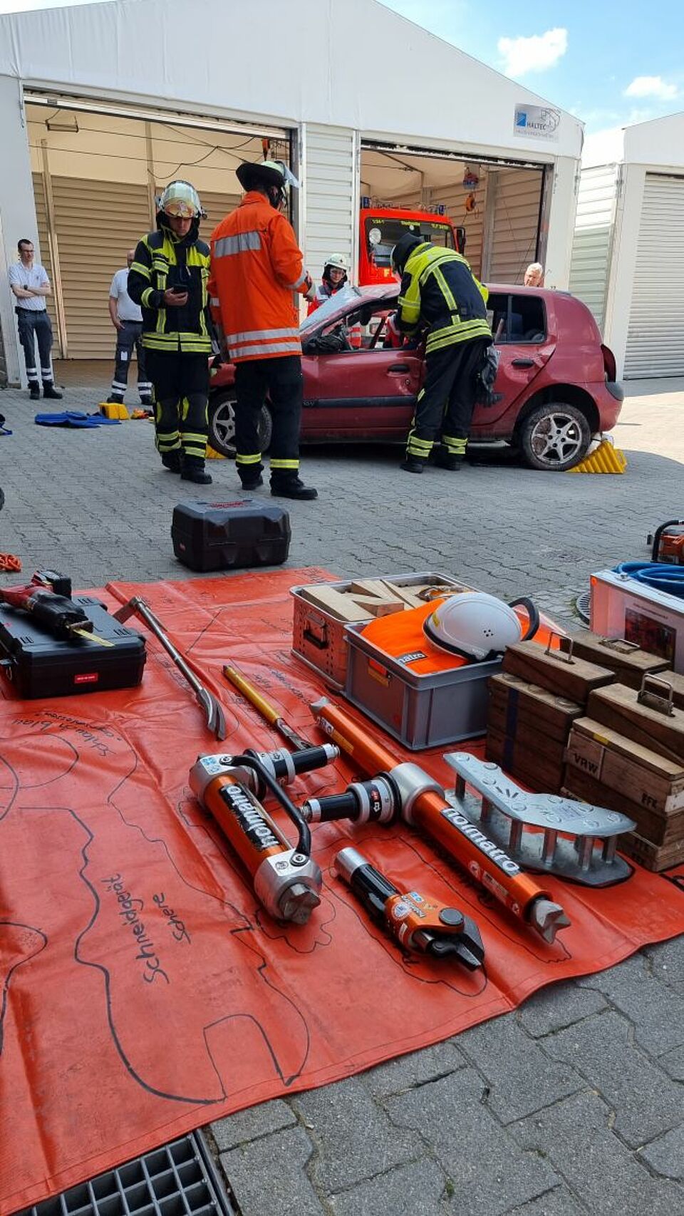 zu sehen sind im Hintergrund ein Übungsfahrzeug und im Vordergrund einige Geräte zur technischen Rettung der Feuerwehr