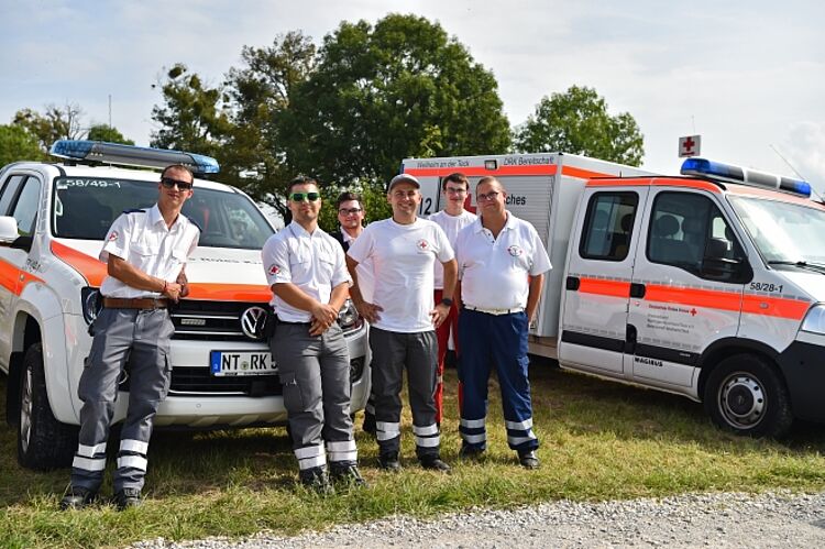 zu sehen ist eine Gruppe von DRK-Helfern vor den Fahrzeugen auf einem Sanitätsdienst