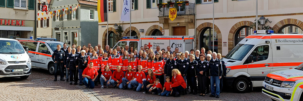 zu sehen ist ein Gruppenbild der DRK Bereitschaft Weilheim mit den Fahrzeugen vor dem Weilheimer Rathaus