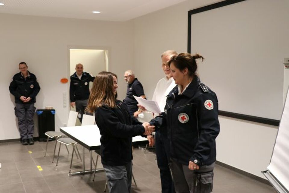 zu sehen ist eine DRK-Helferin bei der Überreichung des Prüfungsbescheinigung